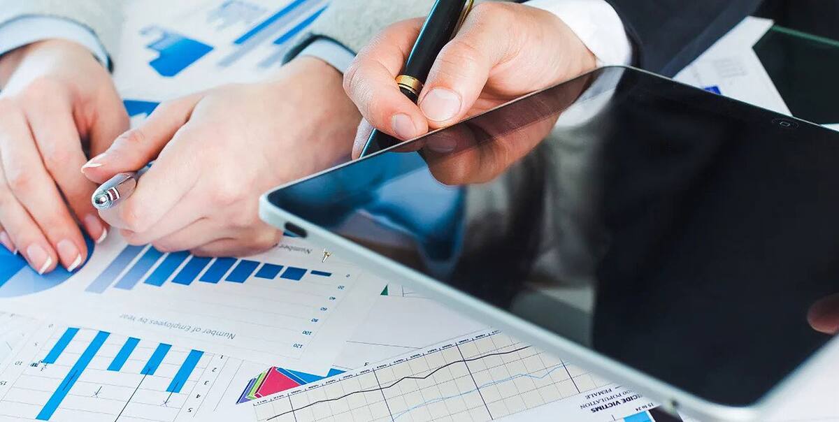 Accountant reviewing financial reports and charts beside a tablet