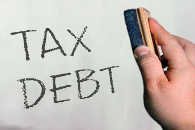 Hand writing the words Tax Debt on paper
